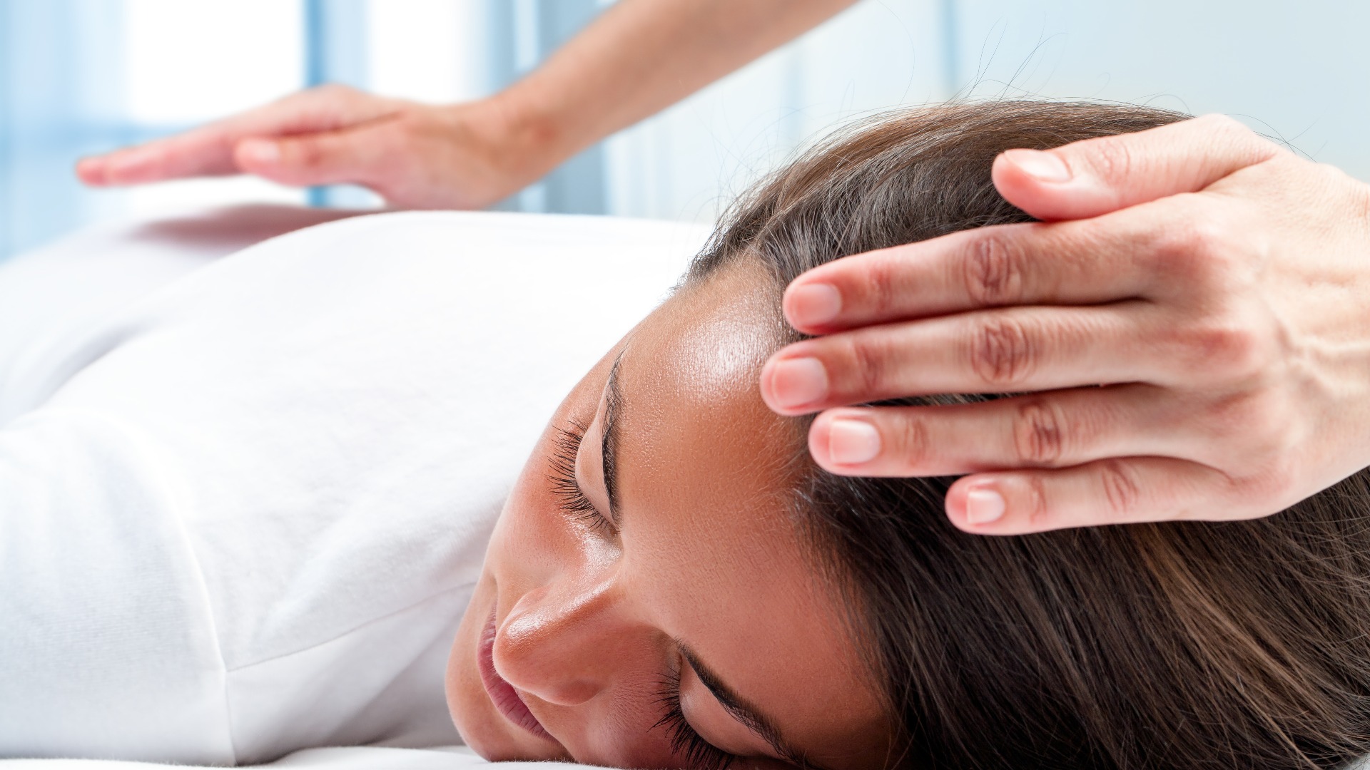 Die Hände des Therapeuten machen eine Reiki-Behandlung bei einem Mädchen.